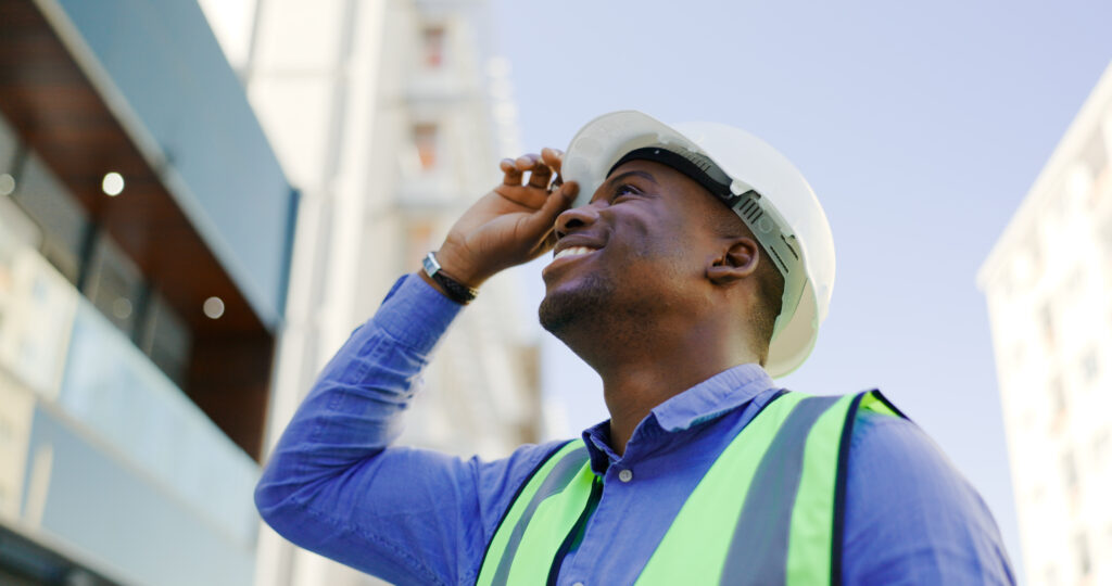 Happy black man, architect and city with helmet for construction, architecture or building on site.