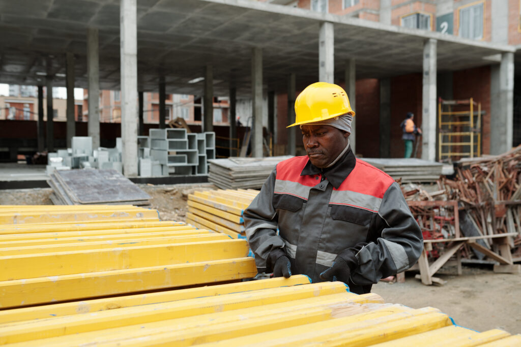Mature black man in workwear standing by pile of building materials